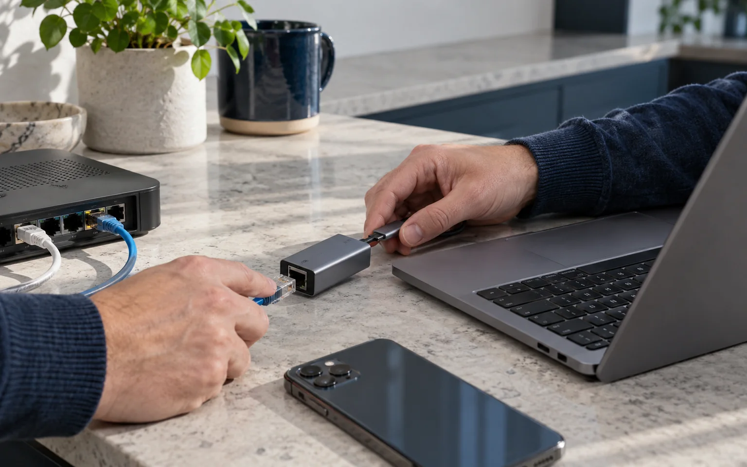 手部将USB-C网络适配器接入笔记本,旁边放有手机和Wi-Fi网关